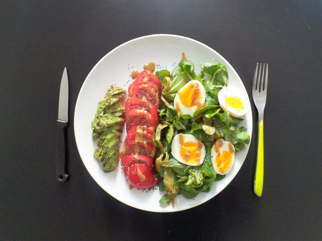 Un exemple de salade avec des ingrédients riches en omégas 3 : avocat, mâche, oeufs, huile de caméline, graines de chia