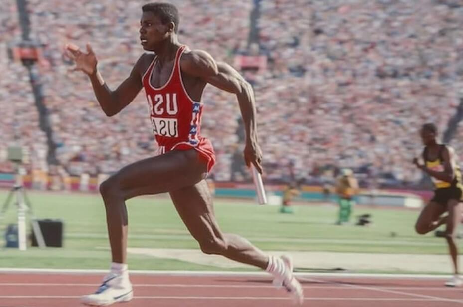 Carl Lewis en pleine course athletique dans un stade plein