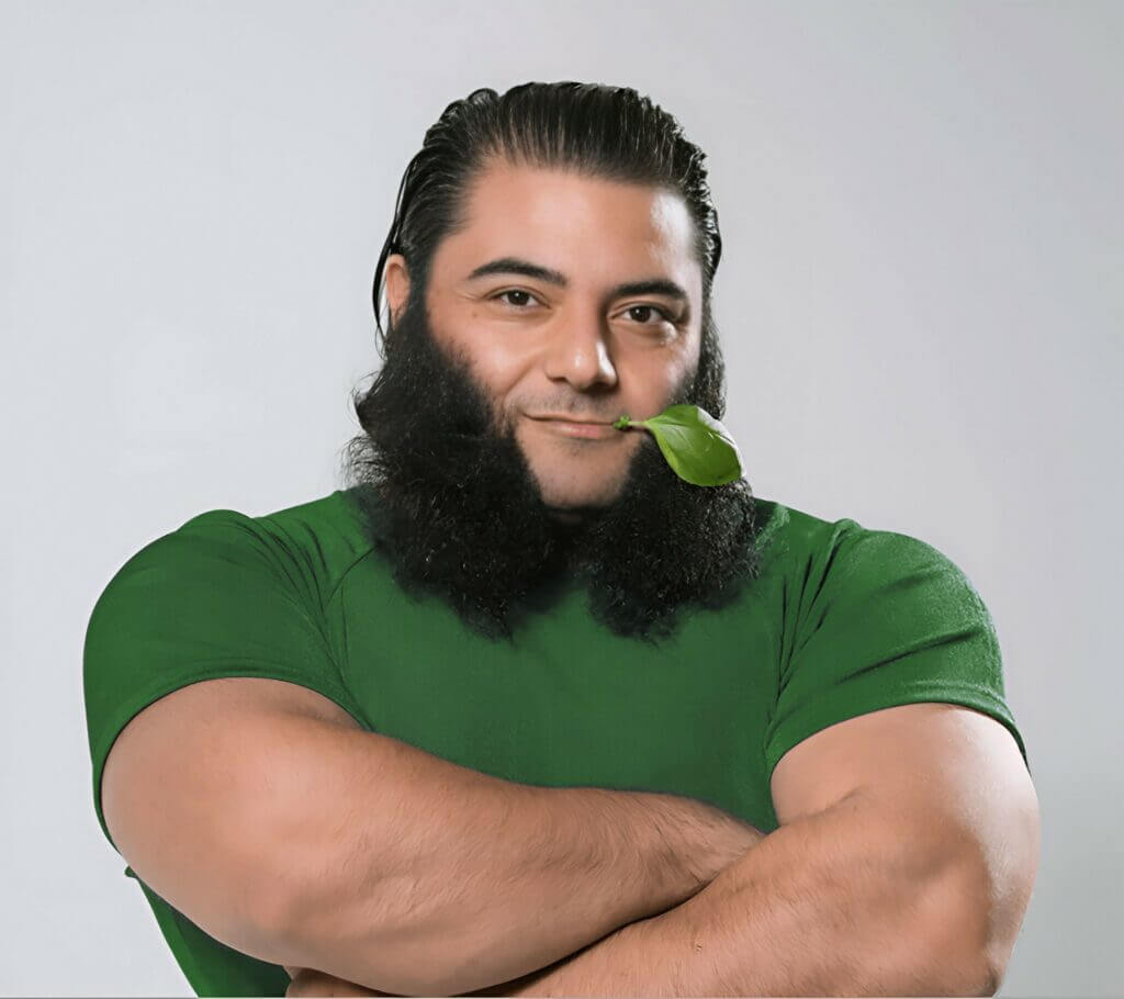 Patrik Baboumian en vert sur fond gris avec une feuille à la bouche